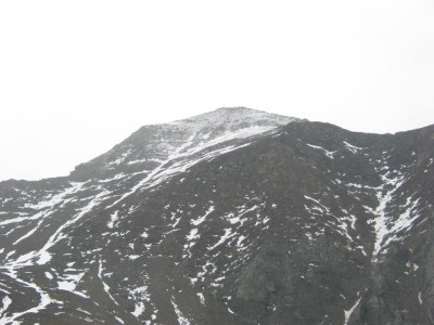 Die schneebedeckte Kreuzspitze mit Gipfelkreuz.